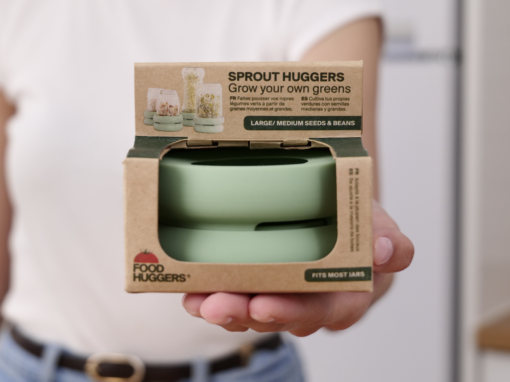 Woman holding in her hand a sprout hugger in its packaging, so you can grow your own greens.
