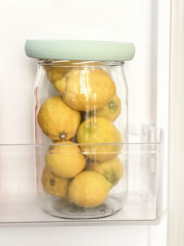 Jar filled with lemons covered with Food Hugger Lid in Fridge door