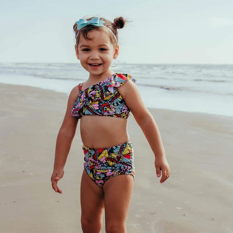 Girl in a SwimZip butterfly love two-piece swimsuit plays at the beach—Best swimsuits.