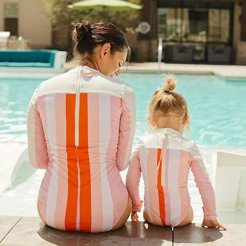 Mom and daughter enjoy sun by the swimming pool in SwimZip Peachy Stripes one-piece swimsuits—How to shrink a swimsuit