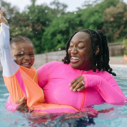 Woman in SwimZip rash guard plays with her daughter in the swimming pool—SPF 50 vs 70: which one to choose