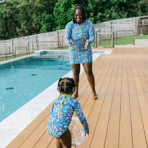 Woman in SwimZip swim dress plays with a child behind the pool.