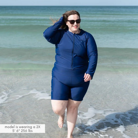 Woman in a SwimZip long swim shorts at the beach—How to swim on your period without a tampon.