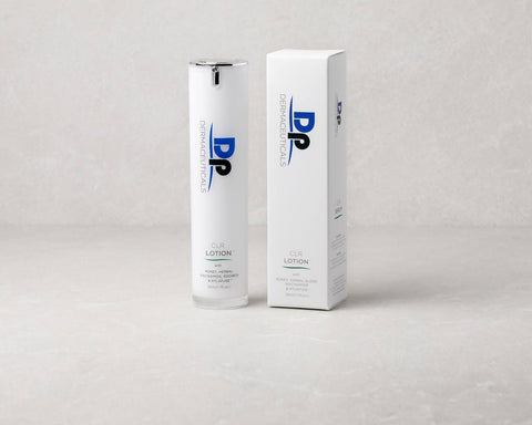 Image of a white, sleek bottle labeled 'CLR LOTION' next to its packaging, featuring 'DERMACEUTICALS' branding, placed on a soft, textured surface.