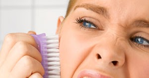 woman brushing her face with a purple brush