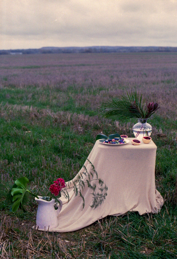 Table in field with flower arrangements on table and the ground.