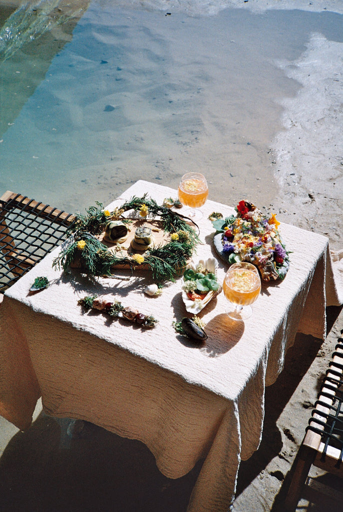 Photo from 0K Studios 'The Cave by the Sea' project showing the dining table situated in the mouth of the cave with the meal laid out on the table. Photo by 0K Studios. 