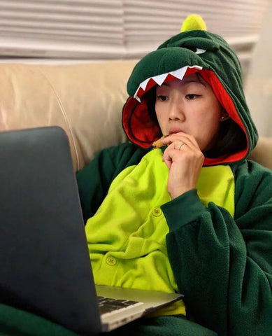 Ragazza indossa un Kigurumi Dinosauro e guarda una serie tv sul computer