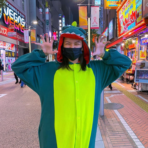 Una ragazza indossa felice un Kigurumi Dinosauro in una strada affollata