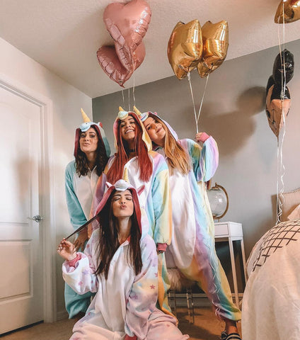 Quattro ragazze a un pigiama party indossano quattro Kigurumi Unicorno (due Arcobaleno, uno Pastel Star e uno Blu)