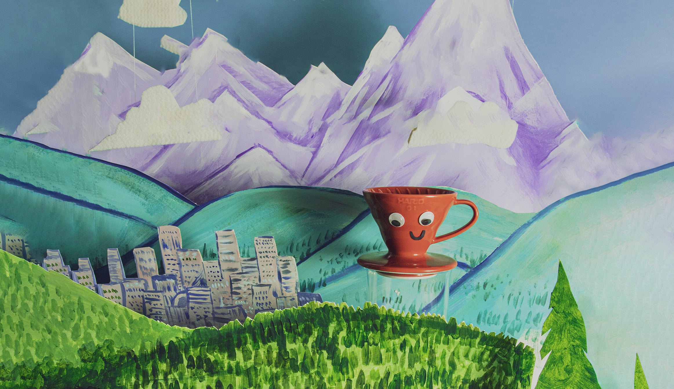 Red conical coffee dripper sitting in a mountain scape made of paper