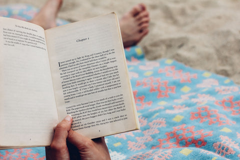 Personne lisant un livre sur une serviette de plage - Rachel Lees Unsplash