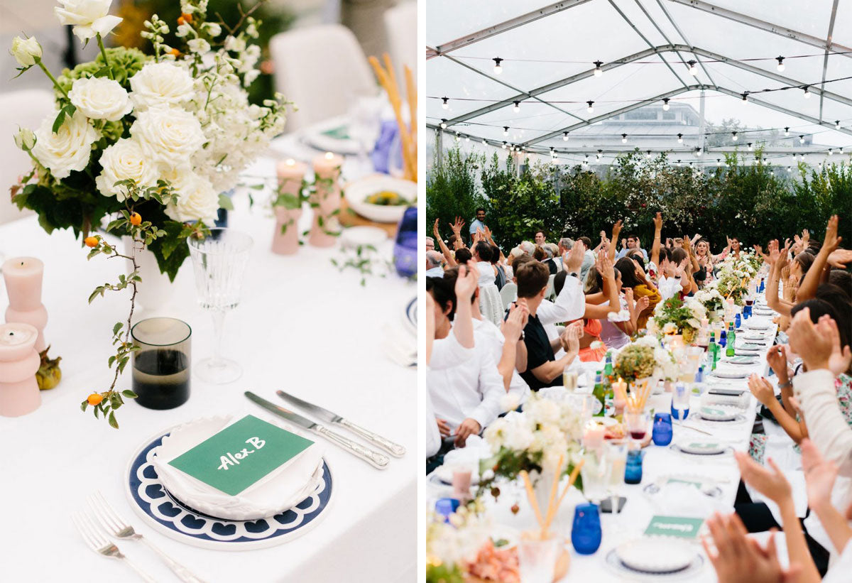 A wedding reception set up in a big tent with many people sitting at long tables and colourful flowers as decoration