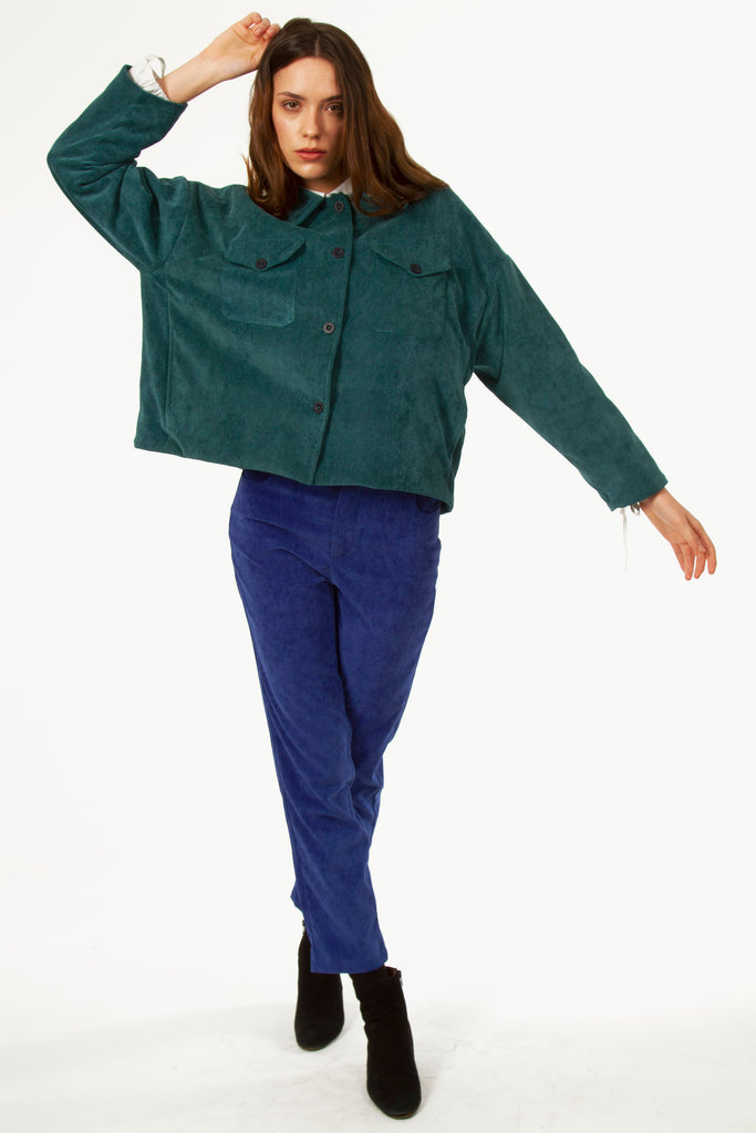 Young woman dancing with a short oversized jacket in emerald green buttoned velvet, diverted utilitarian inspiration for a unique Parisian style this winter