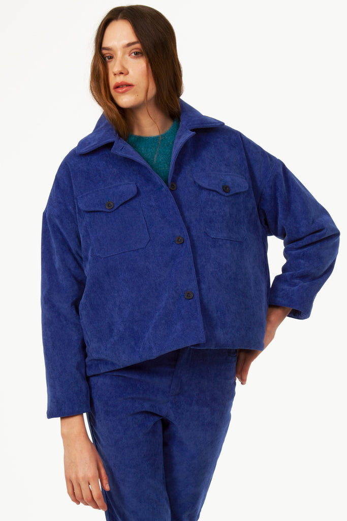 Young woman stares at camera in Klein blue Virgilia jacket front pockets loose velvet warm quality fabric