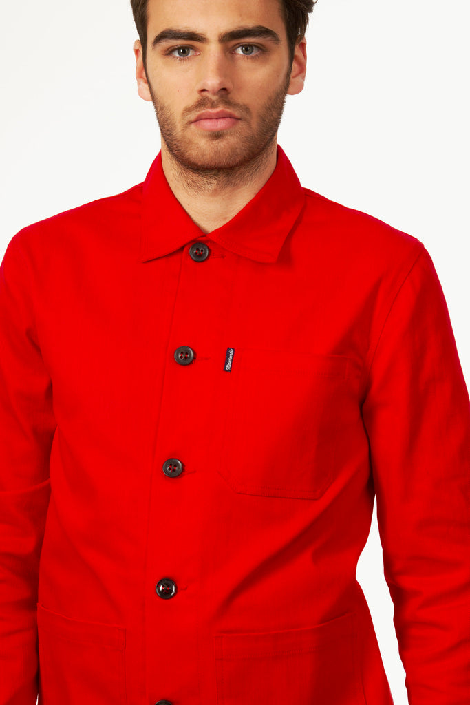 Man with green eyes wearing a buttoned red work blue jacket in thick quality cotton, resistant and solid, vintage inspiration