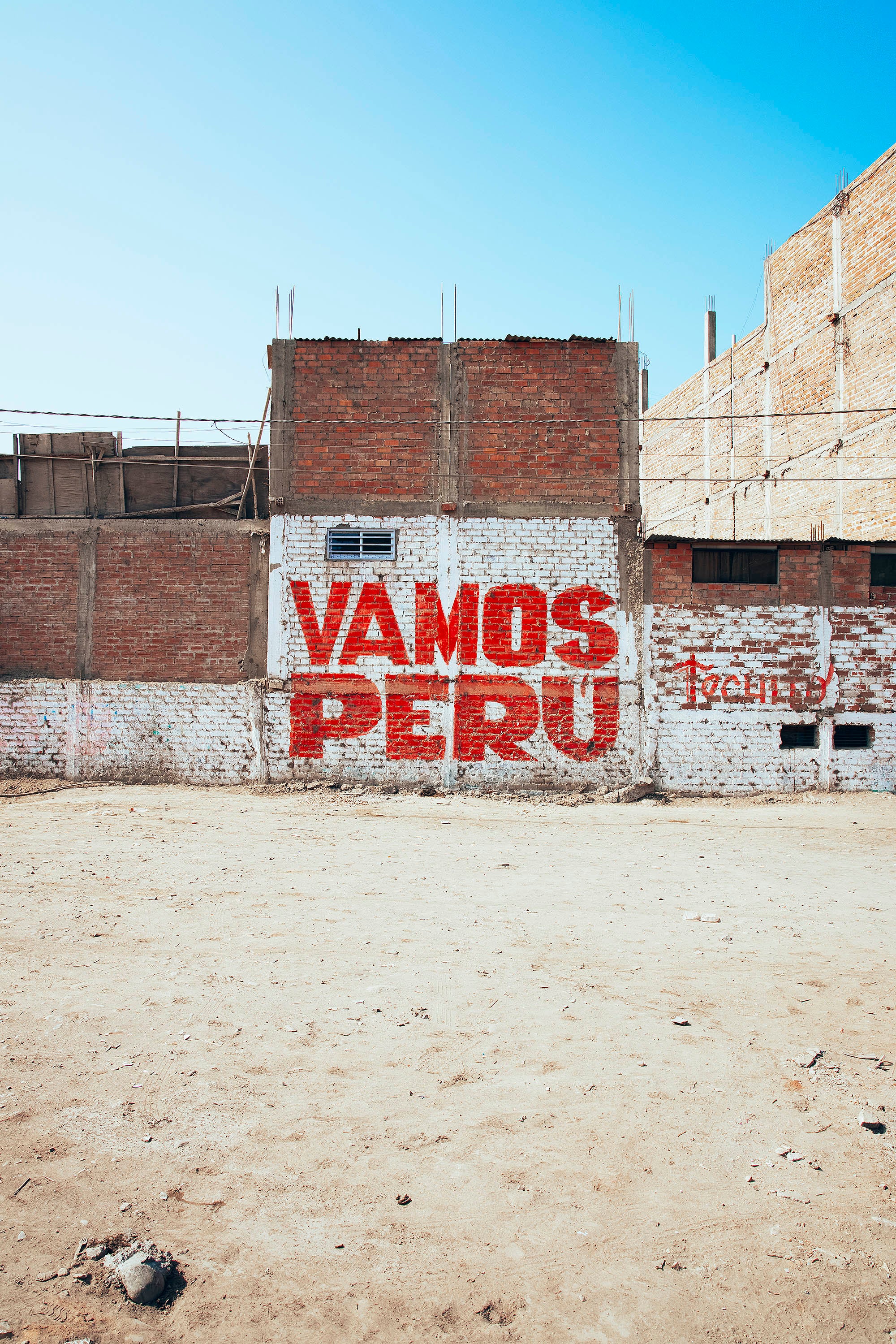 Bidonvilles mur avec tag vamos peru écrit en rouge sur un mur en brique 