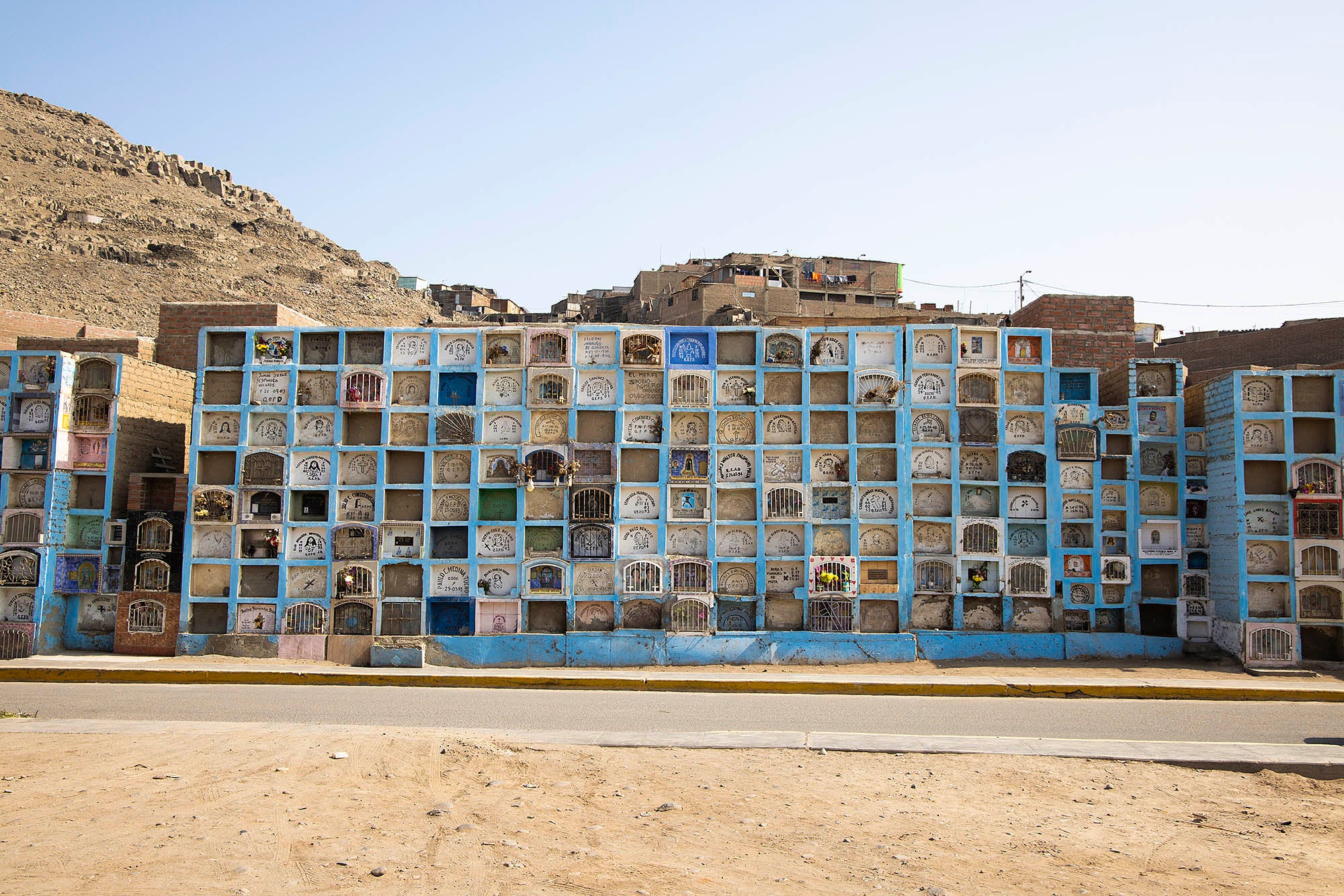Photographie de casiers en pierre pris en photo au pérou devant des bidonvilles voyage inspiration misericordia lima amérique latine