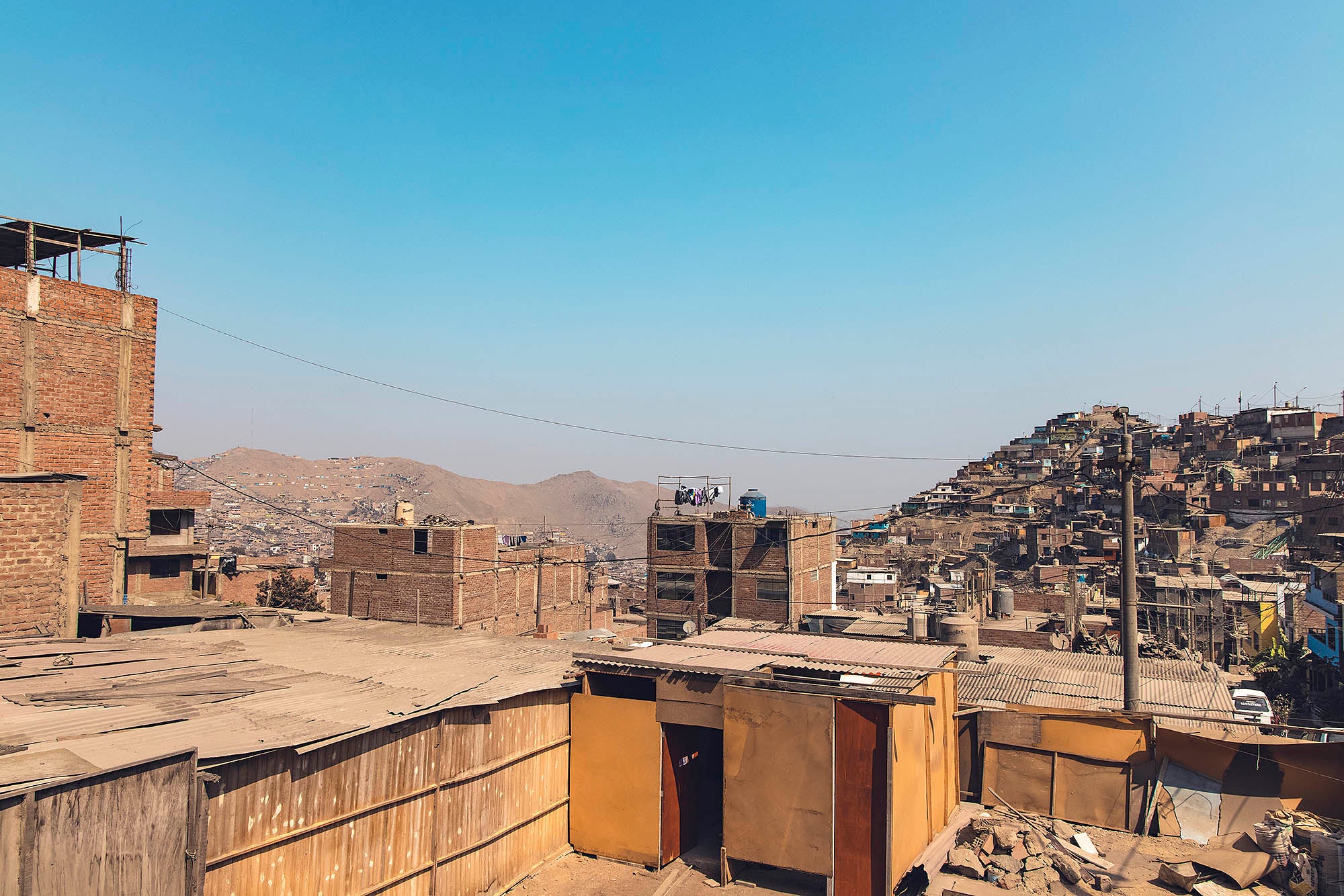 Photographie de bidonvilles au Pérou avec montagnes en arrière plan voyage inspiration lima amérique latine misericordia