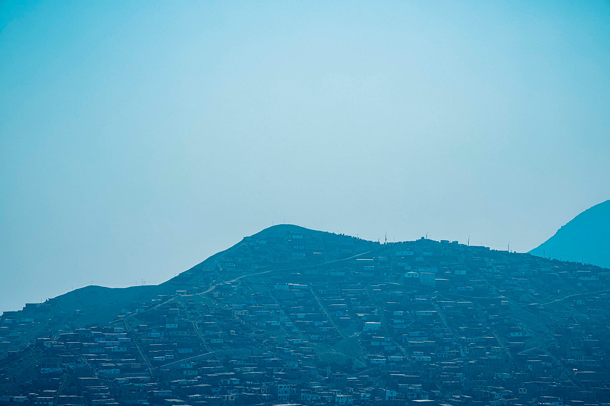 Photograph of a landscape in Peru with slums photographed under a blue sky Lima inspiration latin america misericordia travel