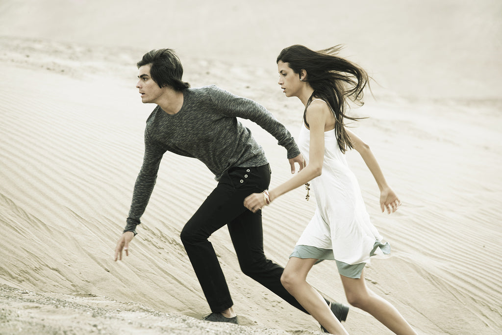 Campagne Collection Misericordia été 2011 couple fort et puissant gravissant une dune de sable en tenues légères