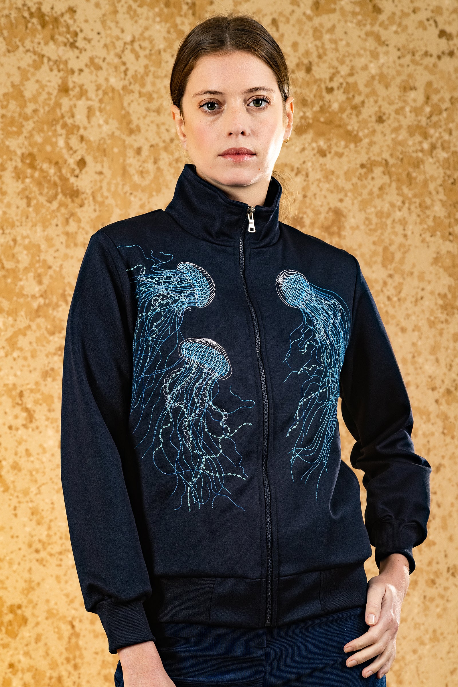 Woman wearing Clasica Medusas Sport Jacket Navy Blue Jellyfish Embroidery Zipper Closure Sportswear Yellow Background Femininity Misericordia Lima Peru