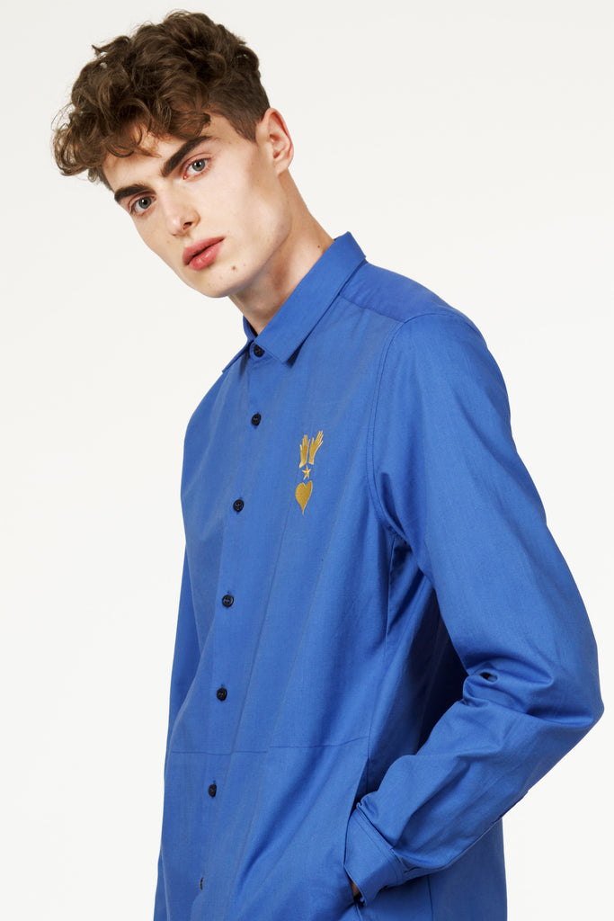 Jeune homme style parisien portant une chemise moderne bleue à poches, broderie sur la poitrine