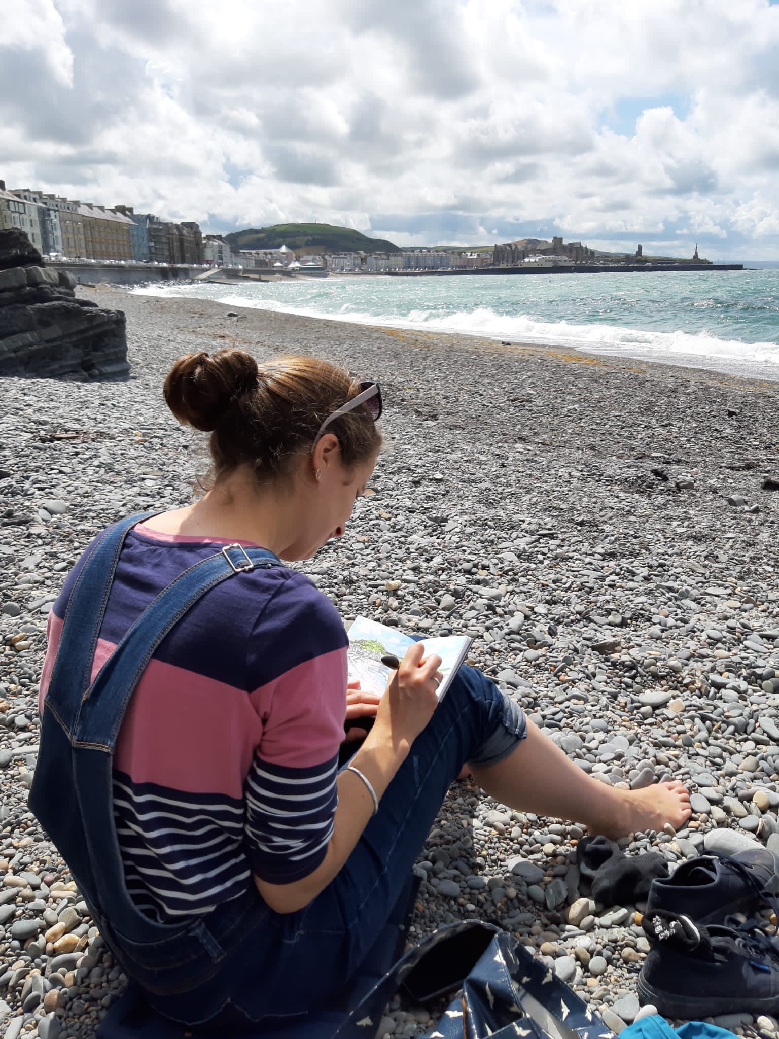 Alice Savery of Alice Draws the Line sketching on Aberystwyth beach