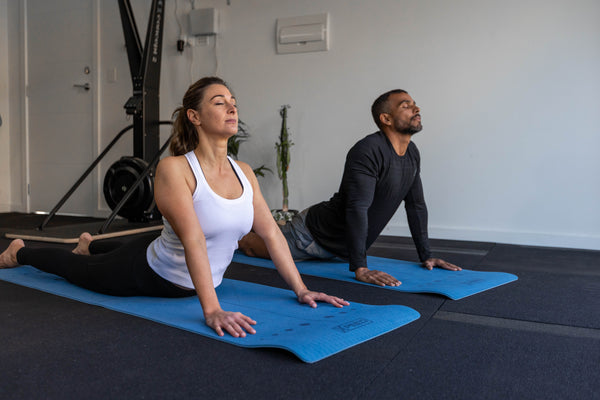 Man And Woman Doing Yoga Pose - Cobra