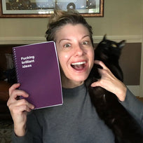 A happy woman holding a cat and a WTF Notebook
