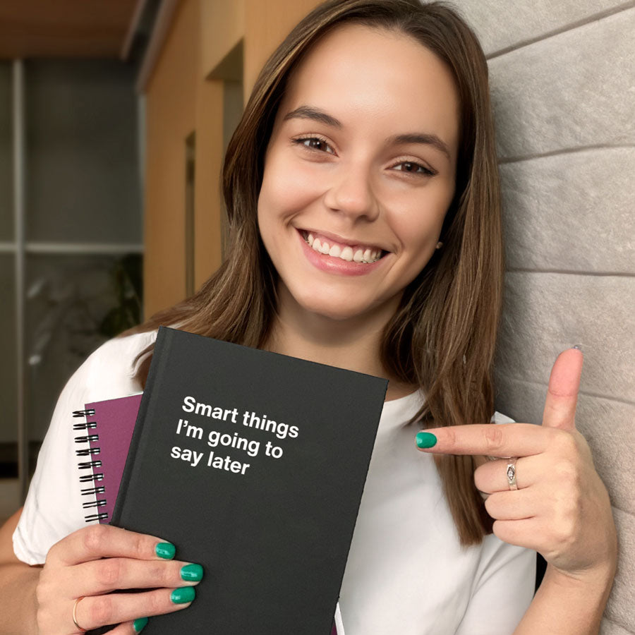 A young woman smiling and holding two WTF Notebooks