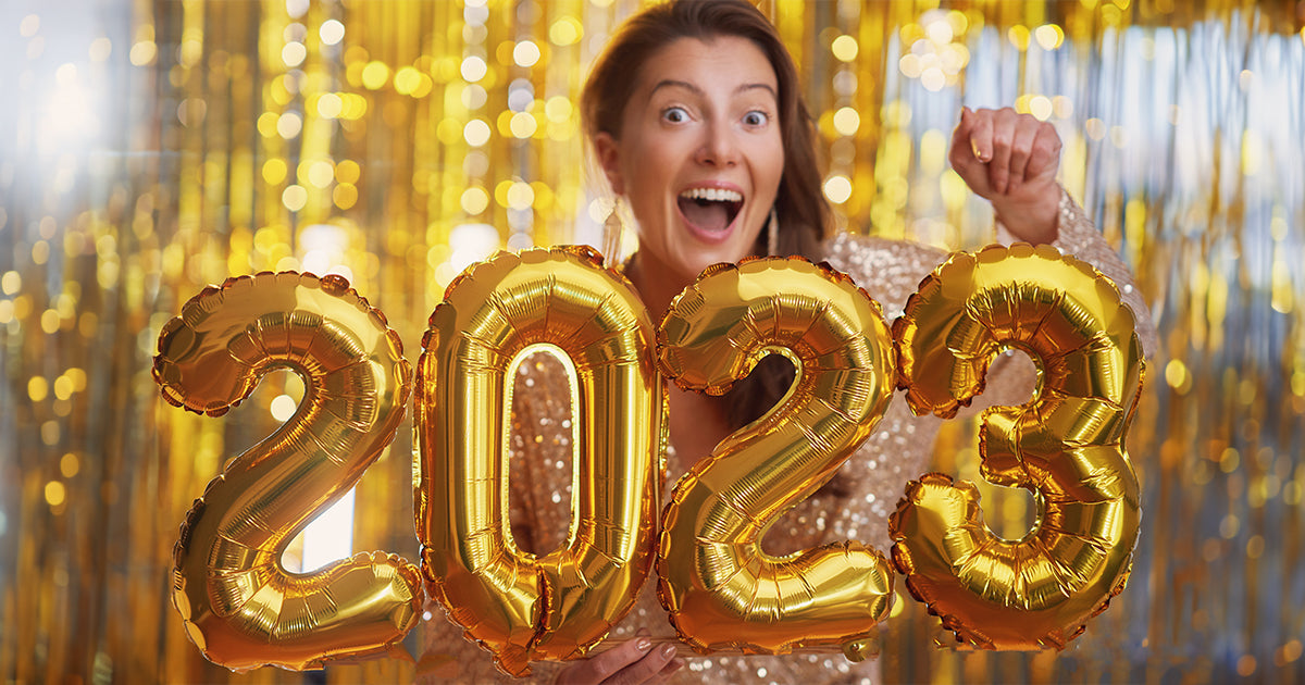 A woman holding number balloons that spell out 2023