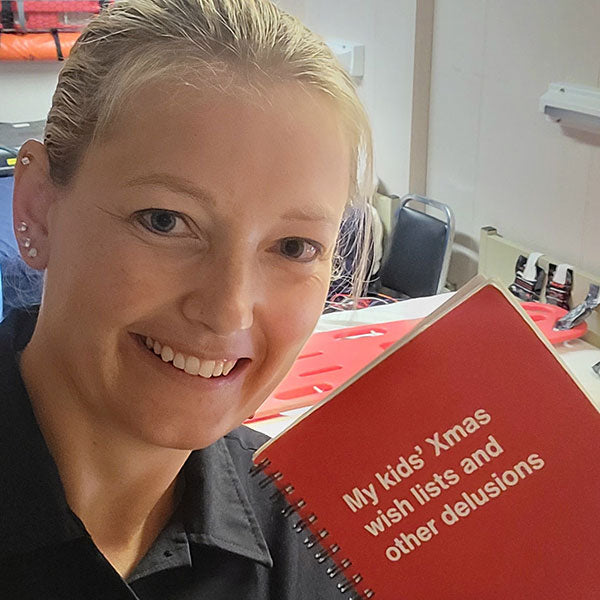 A happy woman posing with her Christmas-themed funny notebook