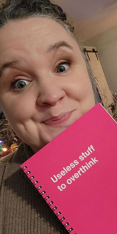 A happy woman with her WTF Notebook in front of a Christmas tree