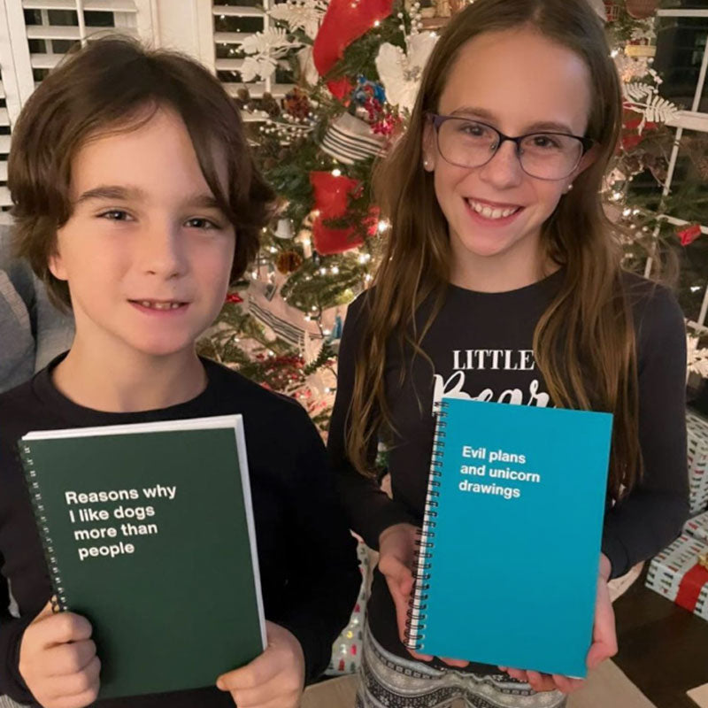 Two happy kids with their WTF Notebooks in front of a Christmas tree
