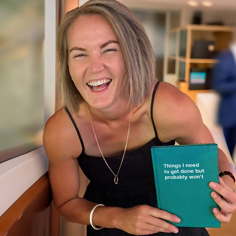 A woman laughing hard at her funny WTF Notebook