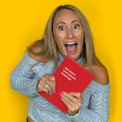 A woman laughing and holding a red WTF Notebook titled 