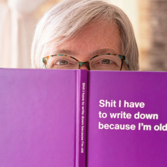 An female senior peeking out from behind her funny WTF Notebook