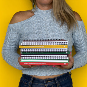 A stack of WTF Notebooks held in front of a yellow background