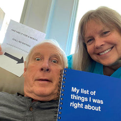 A man and woman smiling and holding a blue WTF Notebook titled 