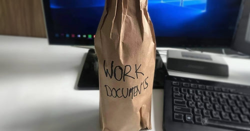 A bottle wrapped in brown paper with 'Work documents' written on it