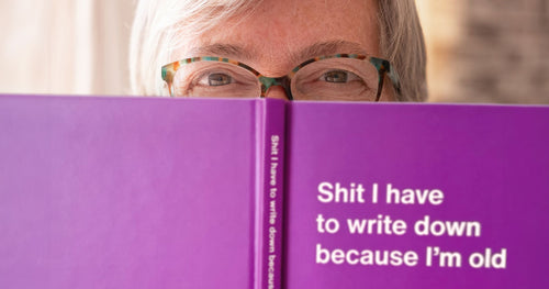 An elderly woman peeking over the edge of her WTF Notebook