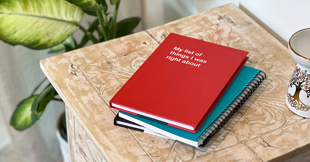 A stack of 3 WTF Notebooks on a coffee table