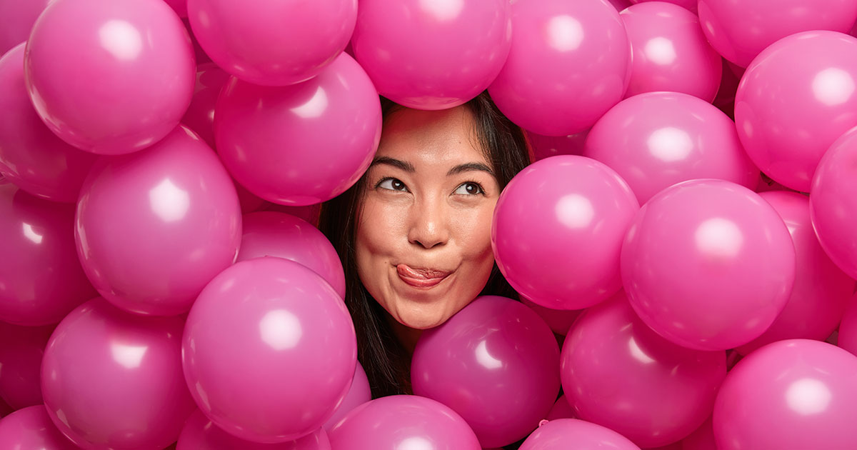 A woman's head sticking out of a pool of pink balloons