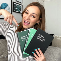 A happy young woman with three WTF Notebooks