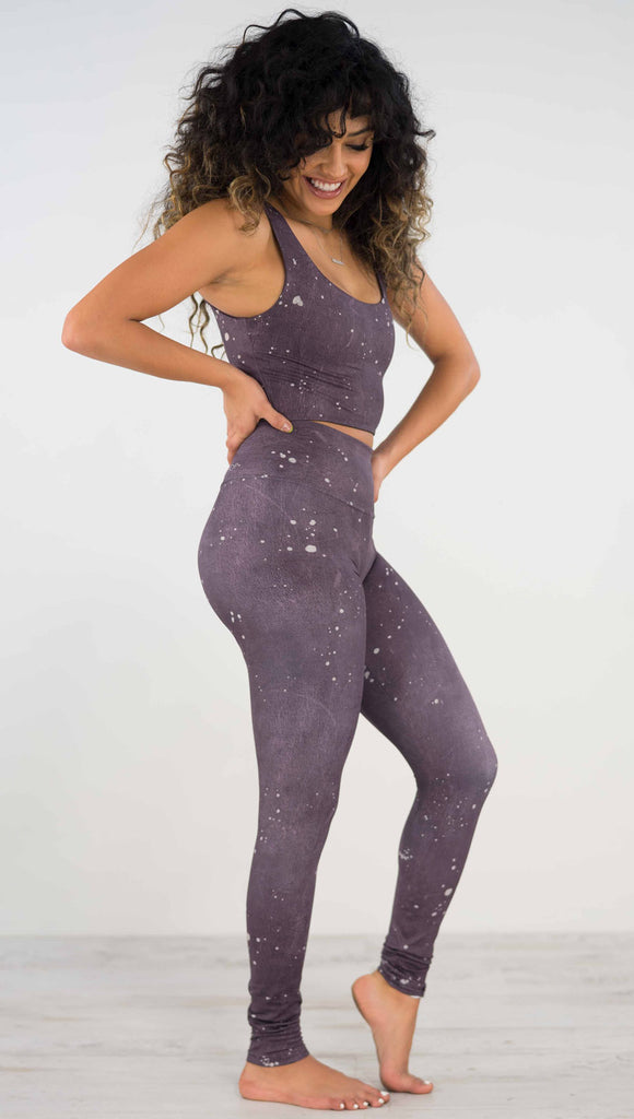 Right side view of model wearing purple high rise athleisure leggings with light gray splatter spots throughout