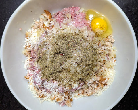 A bowl of ingredients used to make mini meatloaves.