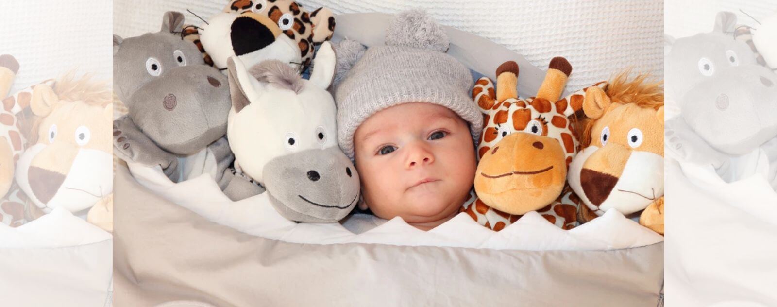 Bébé avec des Animaux en Peluche dans son Lit