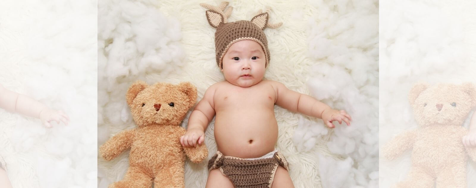 Bebé con su osito de peluche en una cama