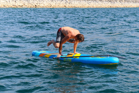 man doing stand up paddle board yoga
